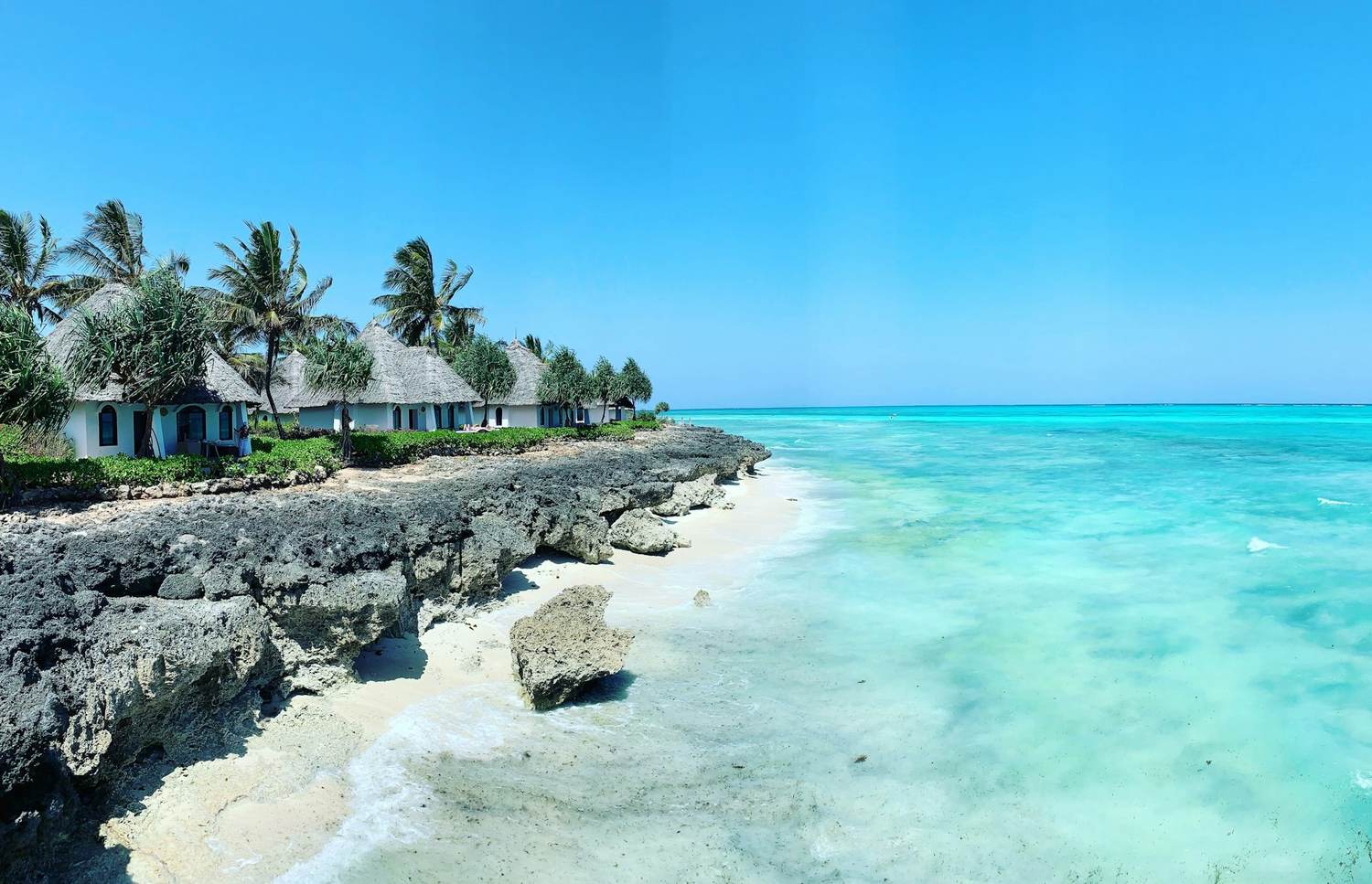 A white-sand beach and turquoise sea seen from a boat off Zanzibar